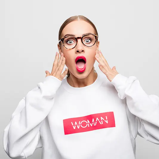 Surprised woman wearing glasses and "WOMAN" sweatshirt